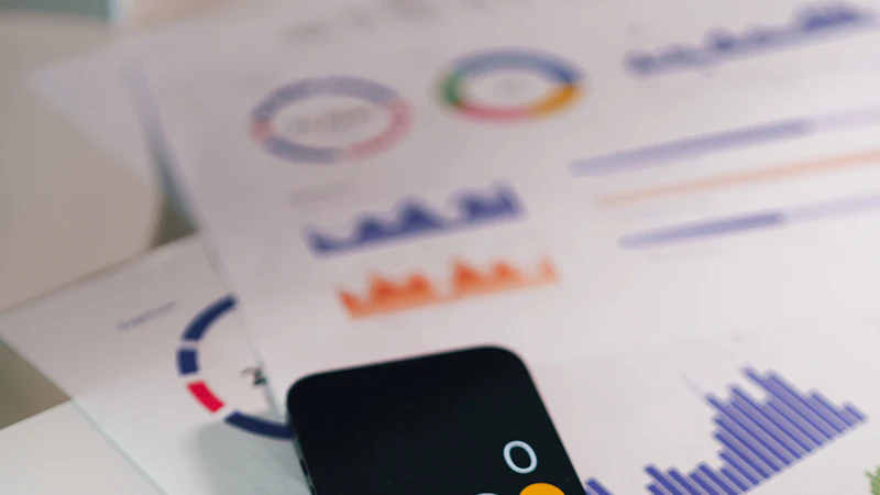 Celular com calculadora sobre relatórios e documentos financeiros